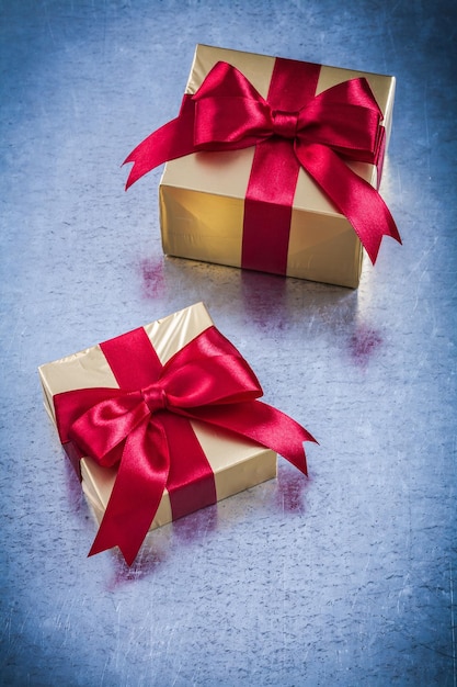 Boxed golden gift with red ribbon on scratched metallic background