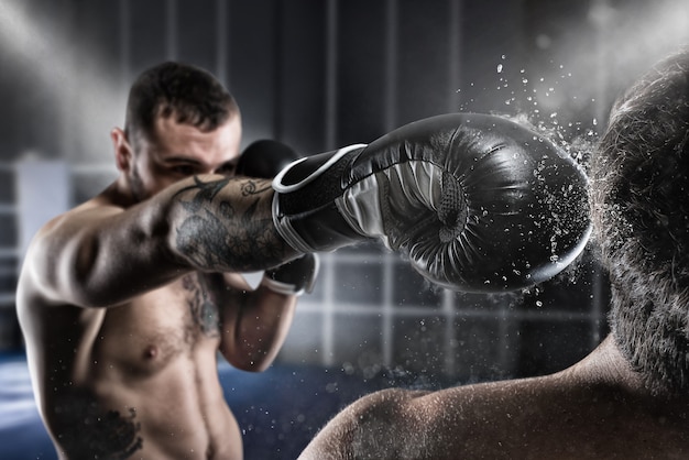 Boxer in a boxe competition beats his opponent with a punch