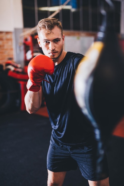 Boxer do boxing training with punchbag on a gym