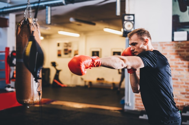 Boxer do boxing training with punchbag on a gym