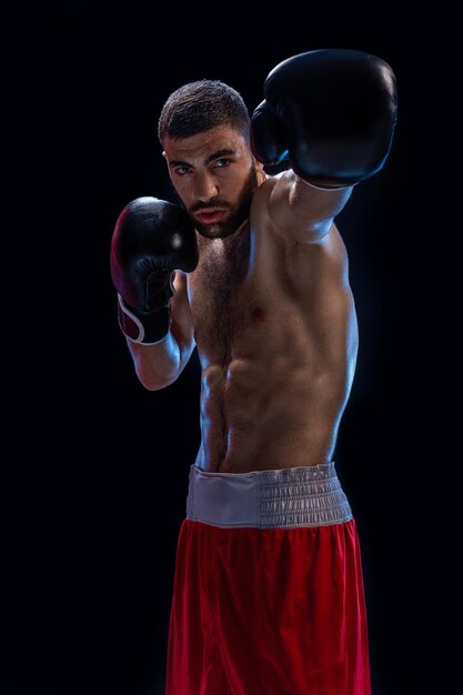 The boxer is ready to deal a powerful blow photo of muscular man on black background