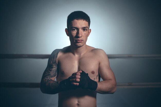 Boxer man posing in bandage on boxing ring Fitness and boxing concept