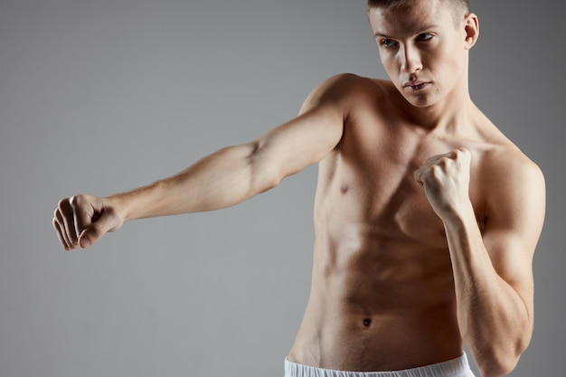 Boxer met een naakte torso training op een grijze achtergrond abs kubussen op de maag kopieer ruimte