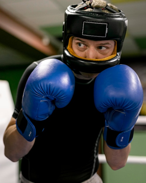 Foto boxer con guanti e casco allenamento sul ring