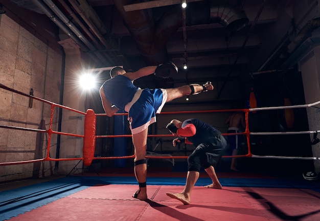 Boxers training kickboxing in the ring at the health club