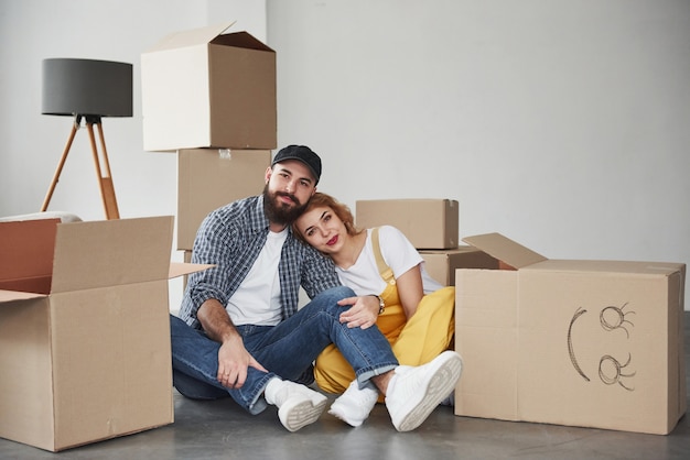 Between boxes. Happy couple together in their new house. Conception of moving