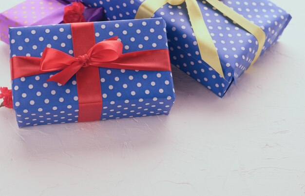 Boxes packed in festive blue paper and tied with silk ribbon on white background, birthday gift, surprise