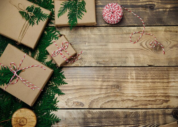 クラフト紙に詰められた箱、木製の背景に枝。環境にやさしい素材。クリスマスとお正月。