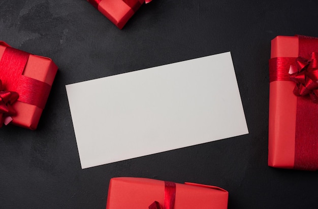 Boxes packed in red paper and tied with ribbon on a black background gifts