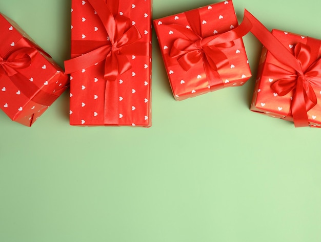 Boxes packed in red paper and tied with ribbon on a green background gifts Copy space