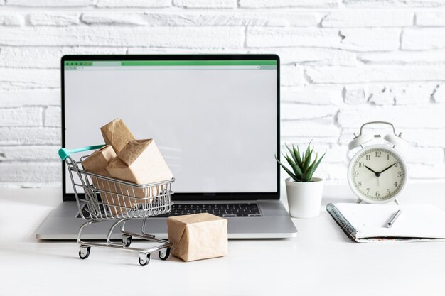 Photo boxes in a trolley on a table with laptop concept of online shopping