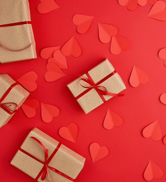 Boxes wrapped in brown kraft paper and tied with red thin silk ribbon on a red