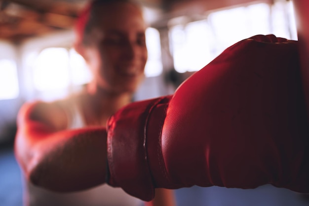 Boxe fitness e sport con guanti da boxe da donna forti per colpire pugni e combattere durante l'allenamento in palestra pugile in forma e atletico femminile che fa un allenamento durante la lezione di autodifesa