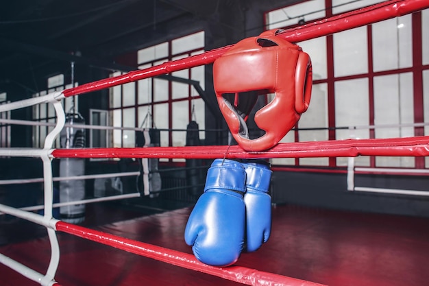 Boxing gloves and headgear on ropes of ring in gym