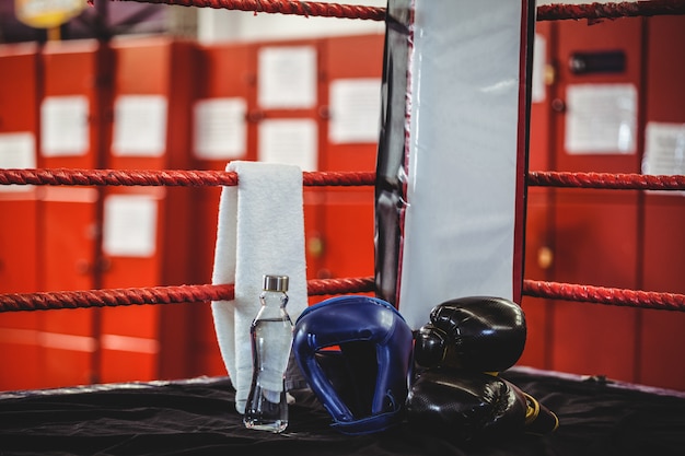 Боксерские перчатки, головной убор, бутылка с водой и полотенце в боксерском ринге
