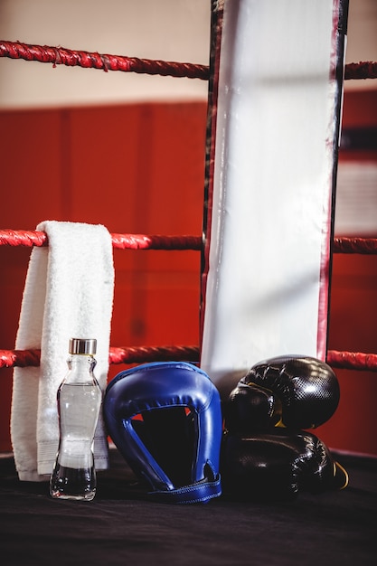 Boxing gloves, headgear, water bottle and a towel in boxing ring