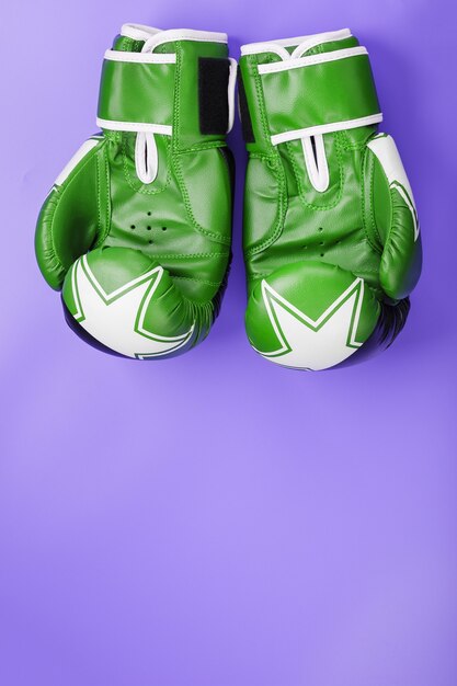 Boxing green gloves on a lilac background.