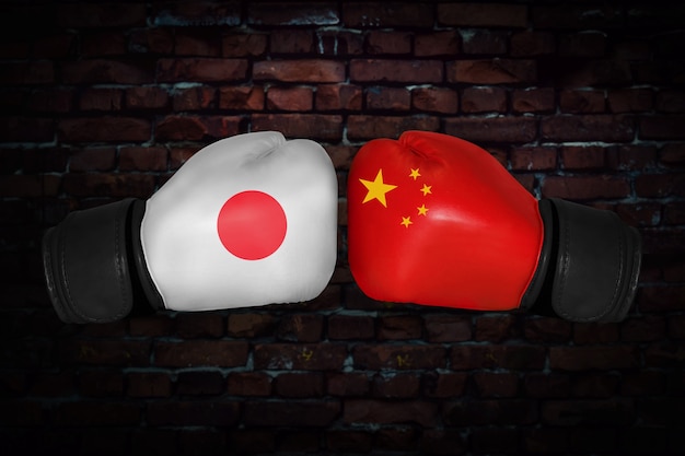 Un incontro di boxe. confronto tra il giappone e la cina. bandiere nazionali cinesi e giapponesi sui guantoni da boxe. competizione sportiva tra i due paesi. concetto del conflitto di politica estera.