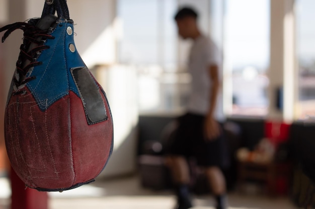 Boxing pear in the gym in focus and an outoffocus boxer in the background