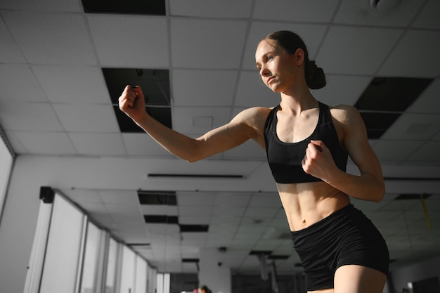 Boxing woman during exercisegray background at gym