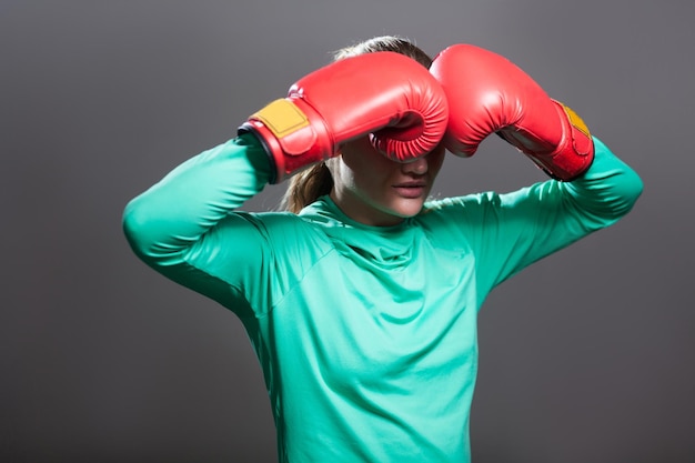 Boxing woman in green sportwear and red boxing gloves