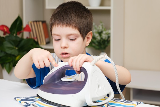 A boy of 4 years learns to hold an iron