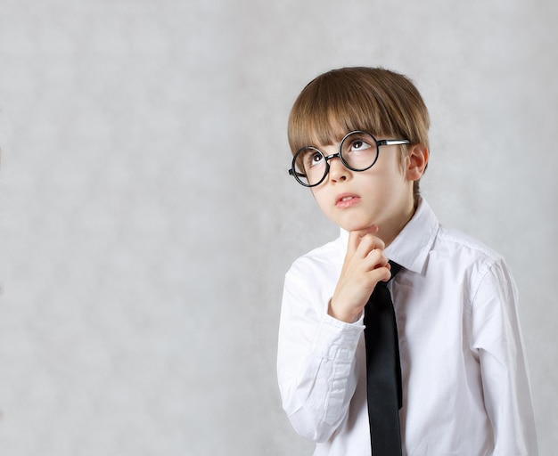 白いシャツに黒いネクタイを着て何かを観察している6歳の男の子