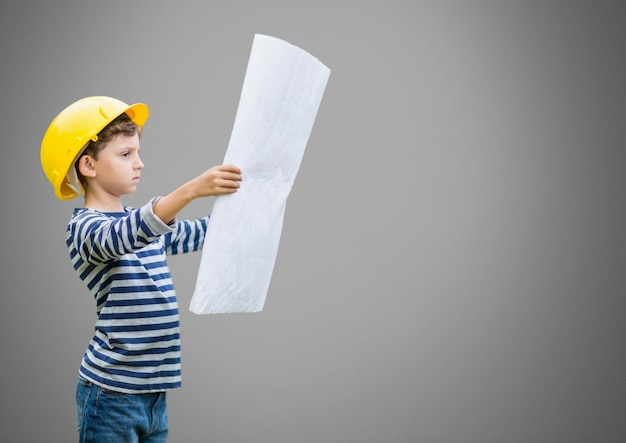 Boy against grey background with building plans blueprint
