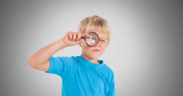 Boy against grey background with magnifying glass