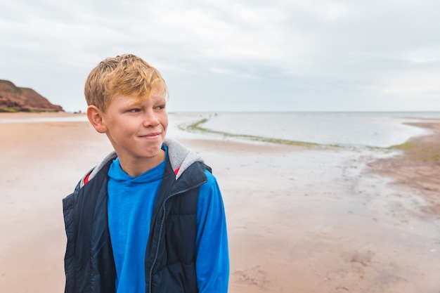 Foto ritratto solo del ragazzo sulla spiaggia il giorno nuvoloso