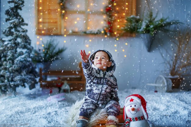 人工白い雪の中の家の雨戸の風景の背景にあるアジアの姿の少年