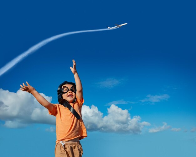 Boy in aviator hat googles with lifted up hands