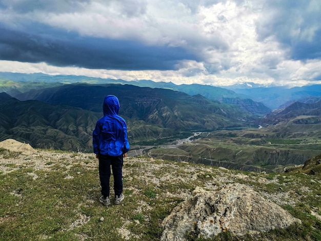 A boy on the background of a breathtaking view of the mountains during a thunderstorm in Dagestan Caucasus Russia