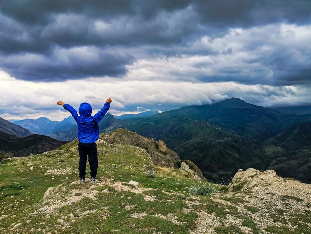 A boy on the background of a breathtaking view of the mountains during a thunderstorm in Dagestan