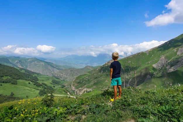 A boy on the background of the green landscape of the Aktoprak pass in the Caucasus Russia June 2021