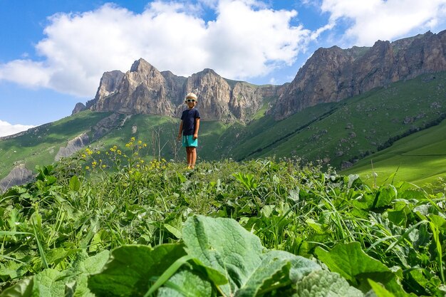 A boy on the background of the green landscape of the Aktoprak pass in the Caucasus Russia June 2021