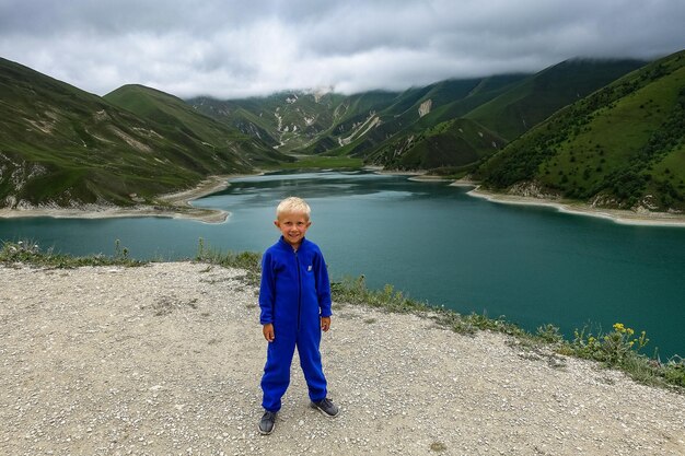 A boy on the background of Lake Kezenoyam in the Caucasus mountains in Chechnya Russia June 2021