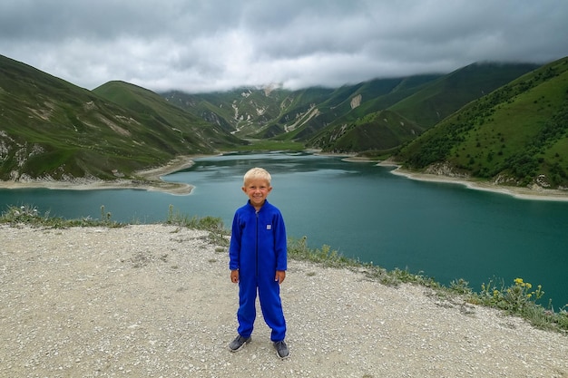 A boy on the background of Lake Kezenoyam in the Caucasus mountains in Chechnya Russia June 2021