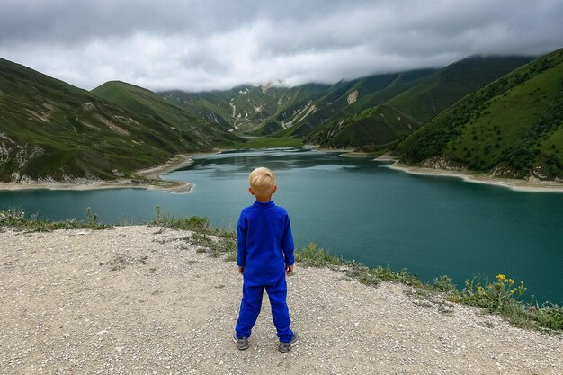 2021年6月ロシアのチェチェンのコーカサス山脈のケゼノイアム湖を背景にした少年