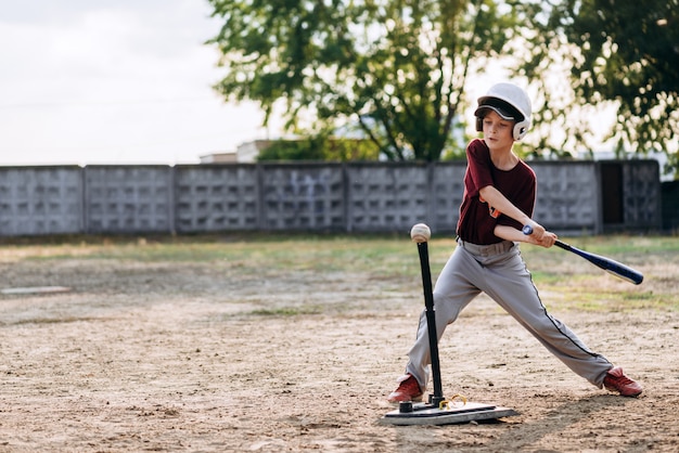 野球選手の少年が野球のバットでボールを打つ