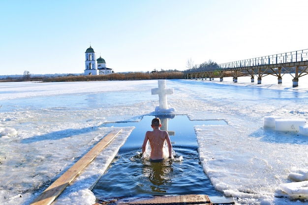 The boy bathes in cold water. Baptism. Bathing in a hole.