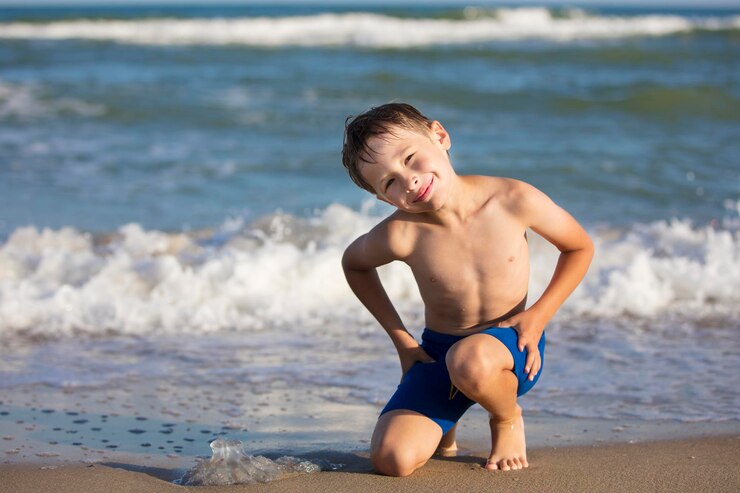 A boy on the beach is playing with a jellyfish Child resting on the beach