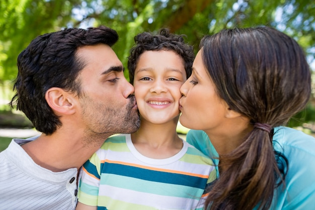 Photo boy being kissed by his parents in park