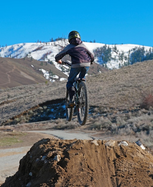 Boy on bicycle jumping over street during sunny day