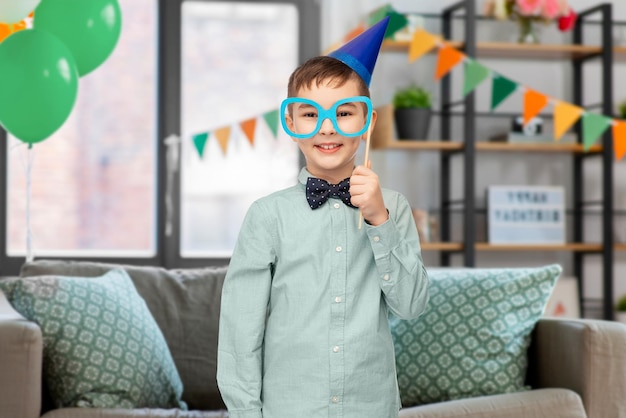 boy in birthday party hat with glasses at home