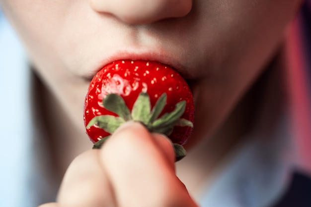 A boy biting red strawberries