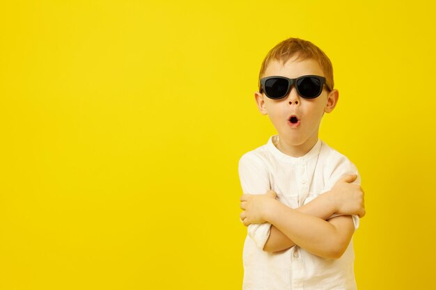 A boy in black sunglasses with his arms crossed poses