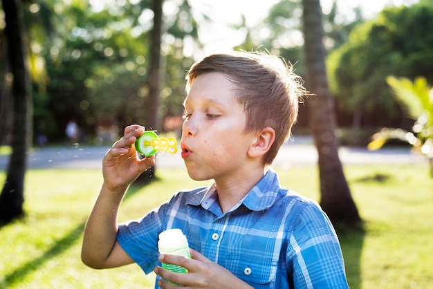 Мальчик дует мыльные пузыри в парке