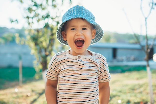 boy in a blue hat is laughing at camera