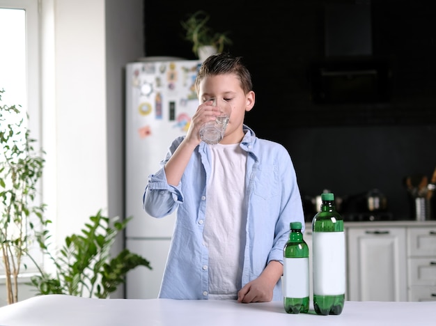 Ragazzo in maglietta blu che beve acqua in cucina